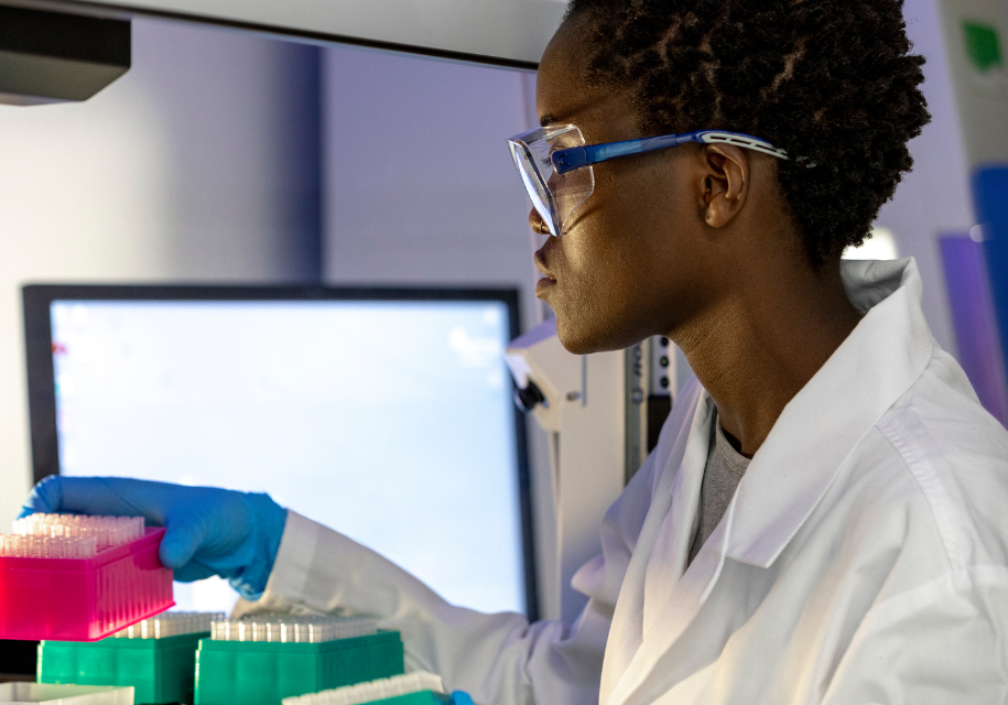 Scientist wearing goggles works with lab equipment.