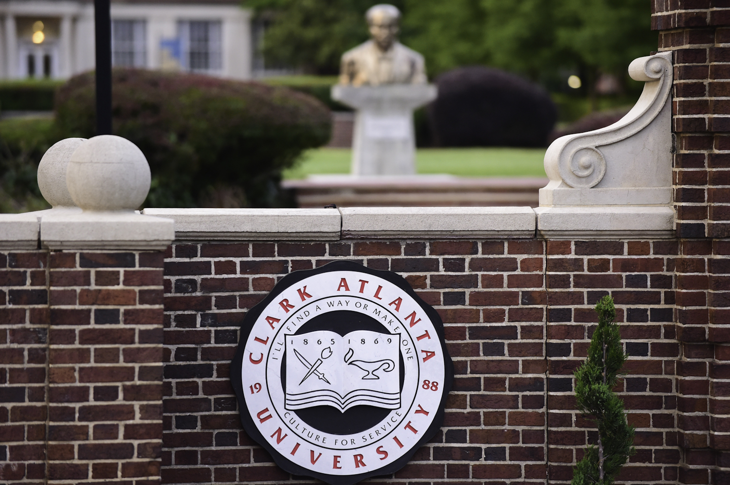Clark Atlanta University sign on a brick wall, statue in the background.