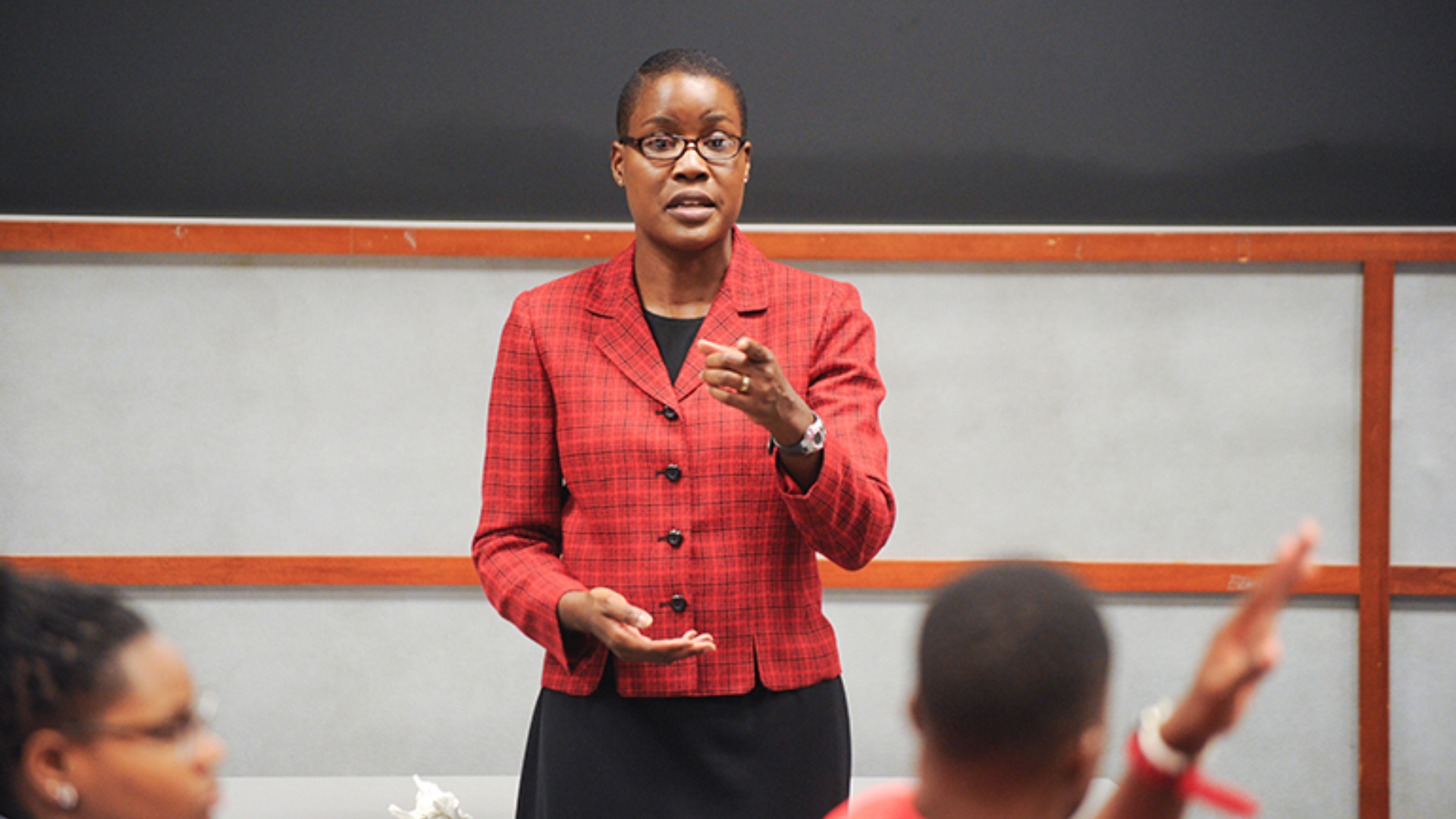 Professor in a red blazer teaching in a classroom.