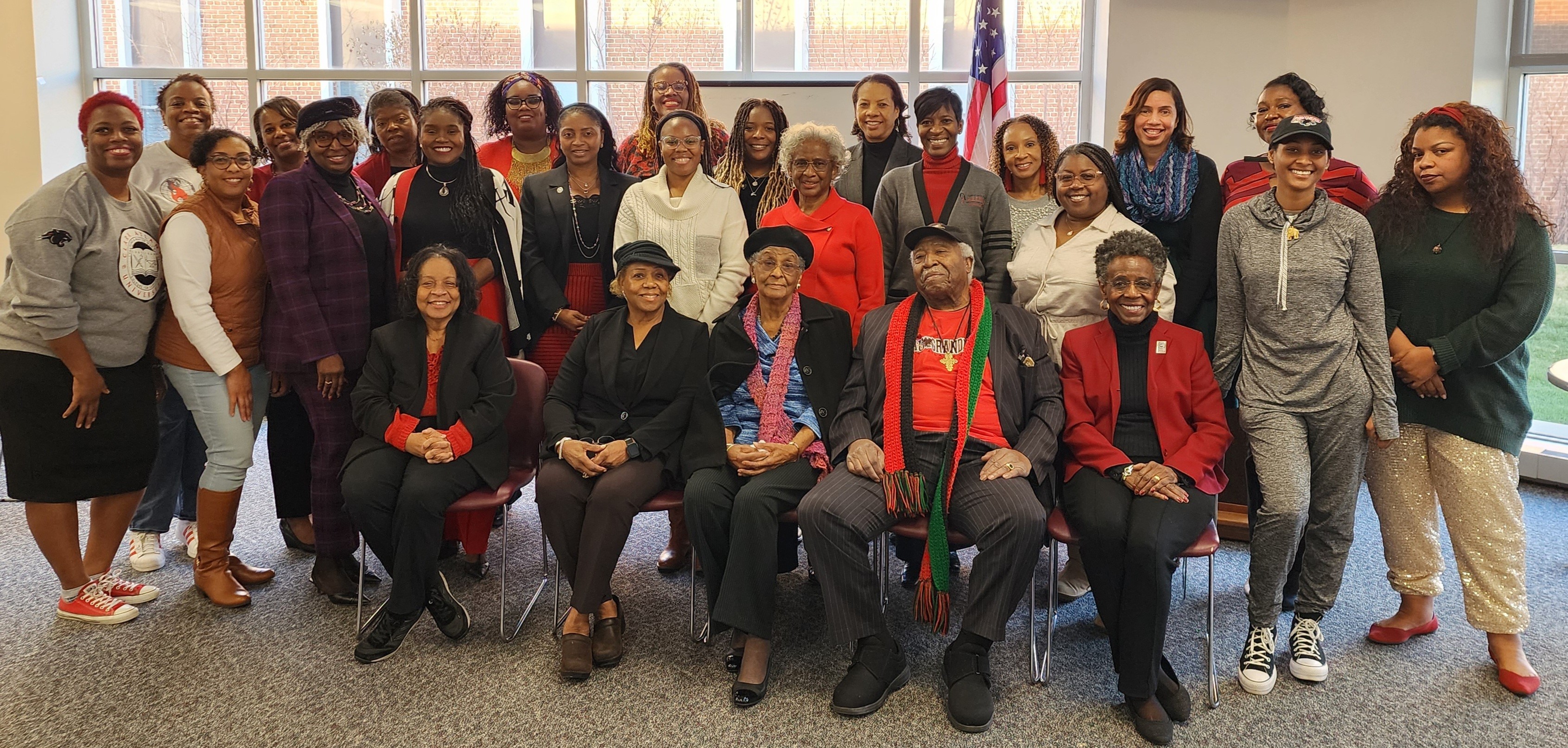 A diverse group of people posing indoors, some seated, some standing.