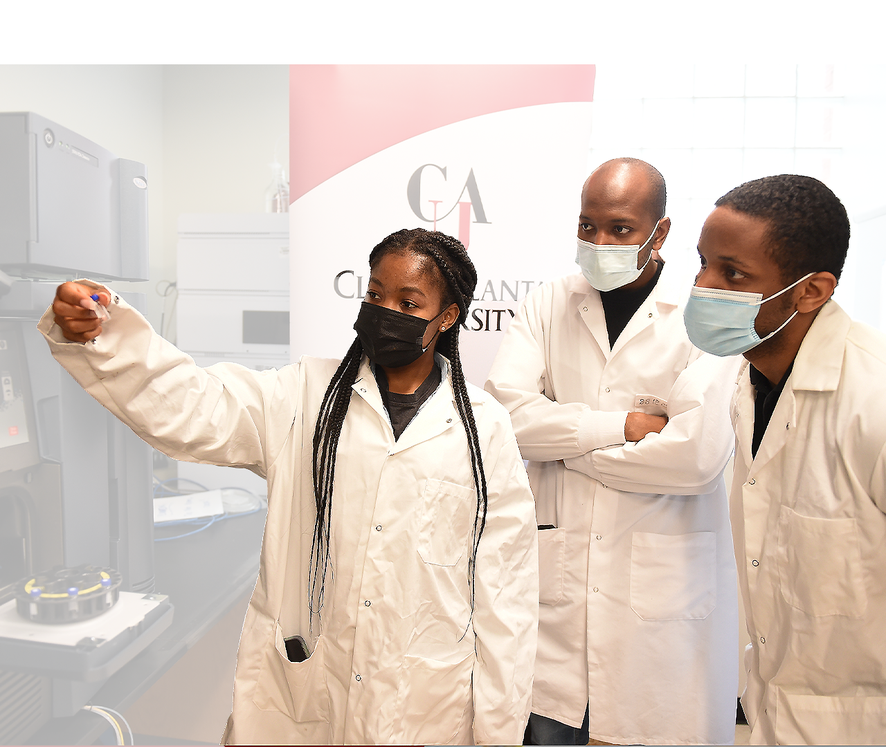 Researchers in lab coats and masks discussing in a laboratory setting.