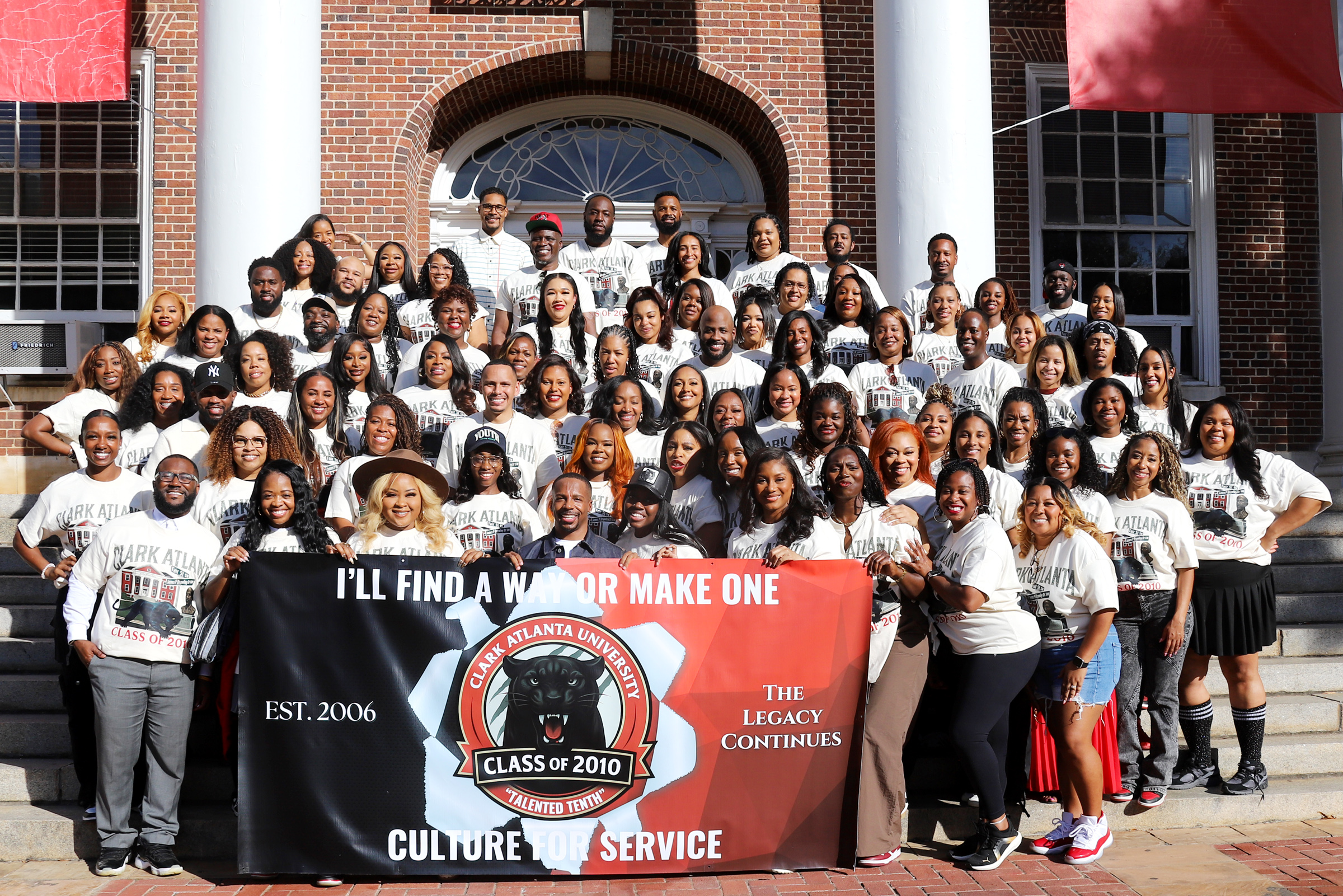 Group of people posing on steps with a banner.