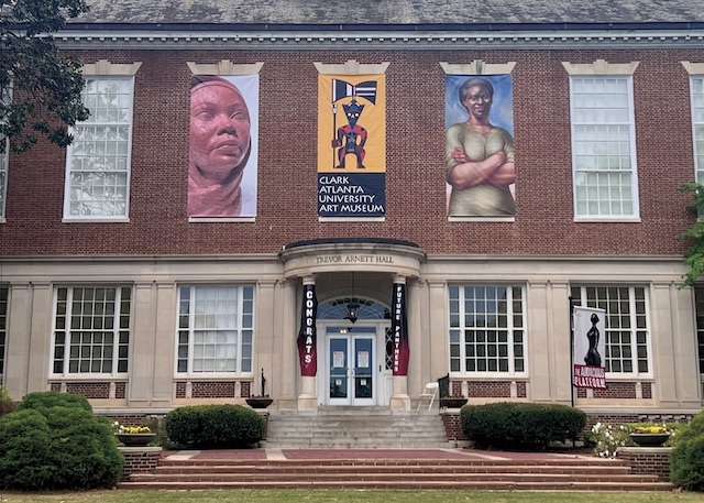 Historic brick library with artworks displayed on its facade.