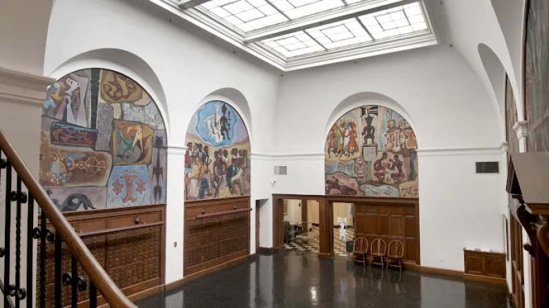 Museum interior with murals and a skylight.