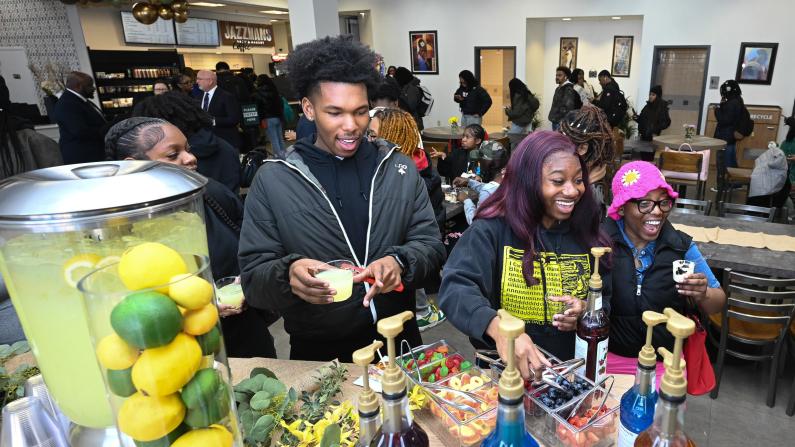 People smiling at juice bar with fresh ingredients.