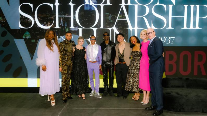 Group of people posing on stage at a fashion event.