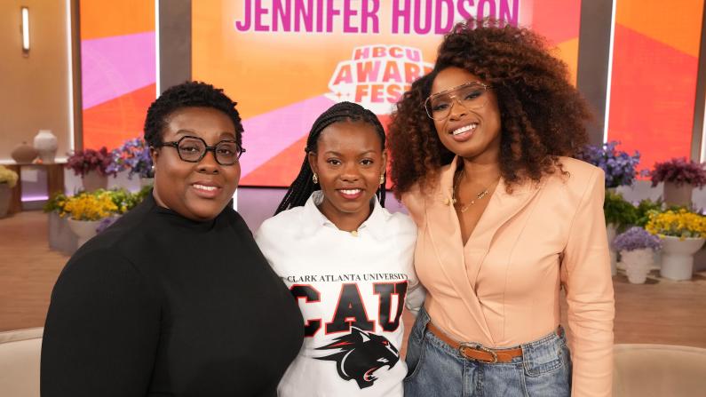 Three women smiling in a studio with a colorful backdrop.