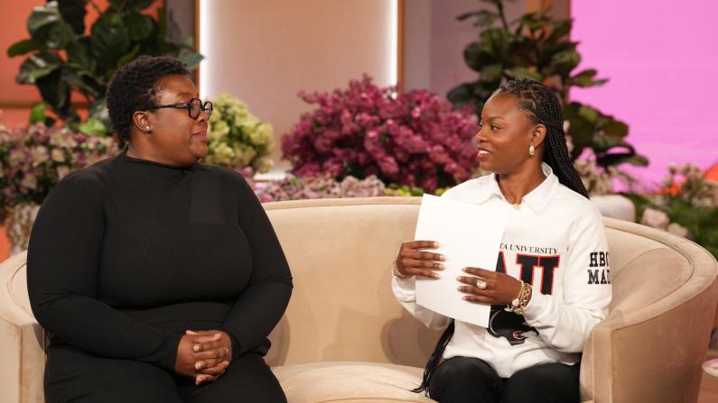 Two people sitting on a beige couch, engaged in conversation.