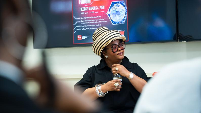 Jill Scott in a striped hat speaking, seated in front of a student security forum poster. Photos by Kaden Lymon, Clark Atlanta University Class of 2026