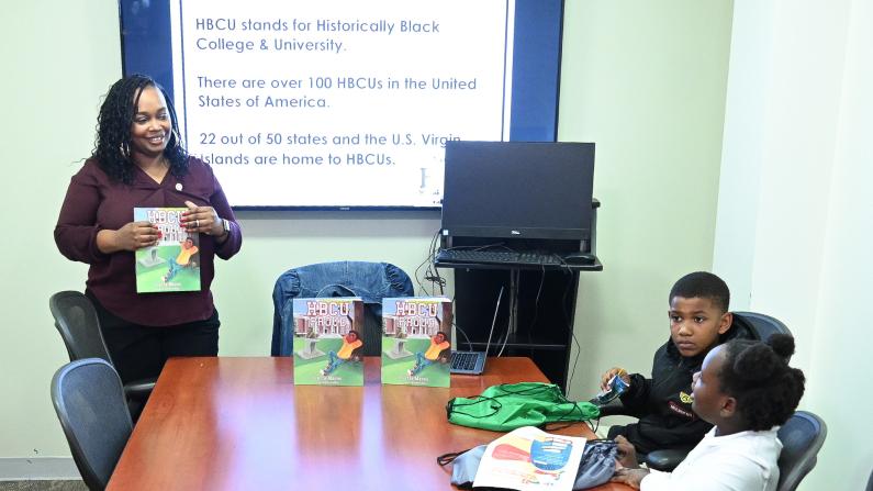 Presentation on HBCUs with a presenter and three children around a table.
