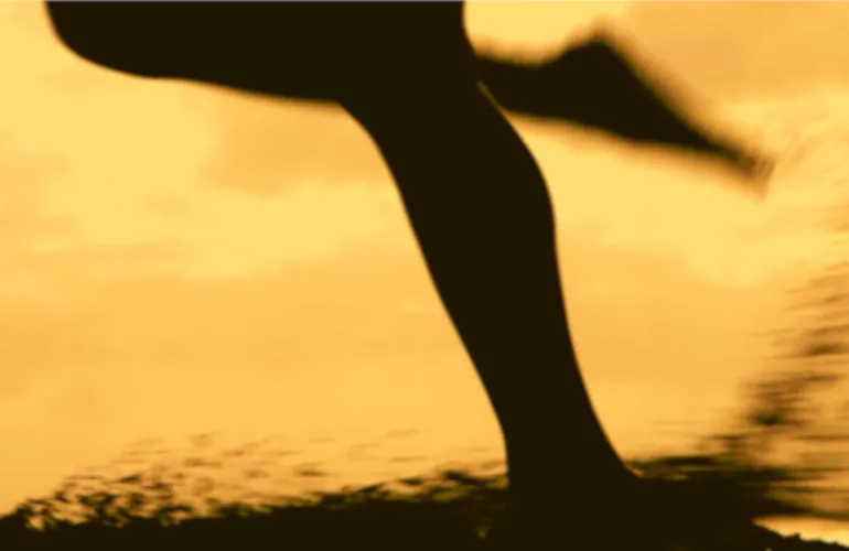 Runner's legs in motion, blurred sepia background.