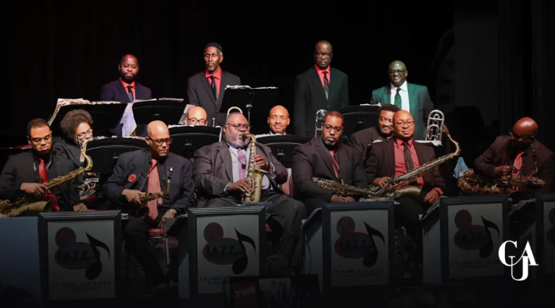 Jazz band on stage, musicians with instruments, wearing dark suits and red ties.