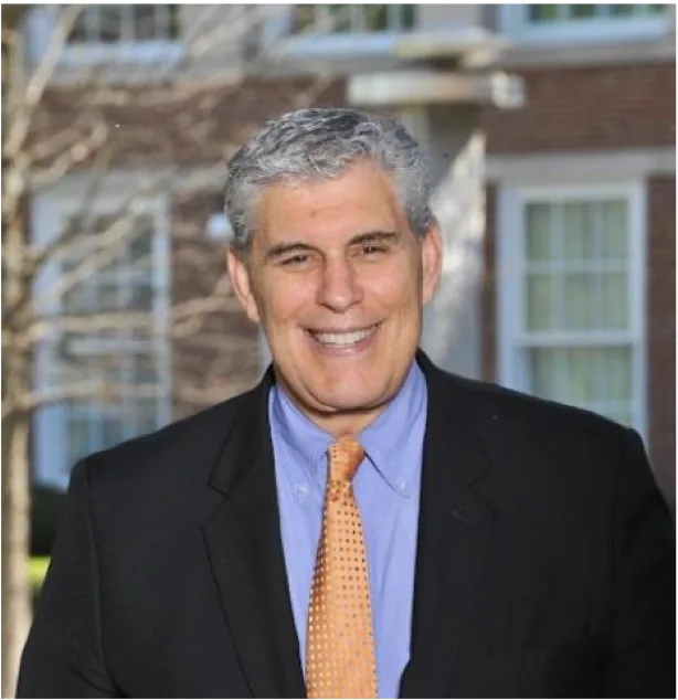 Bruce Berger Professor of Entrepreneurship in suit and tie outdoors, blurred building background.