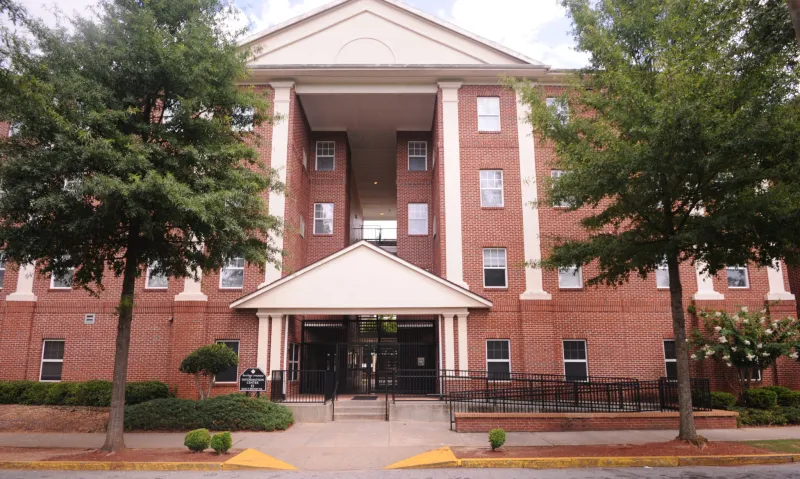 Red brick building with white columns and trees in front.