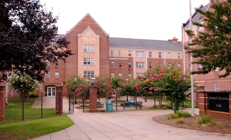 Red brick building with a central courtyard and flowering trees.