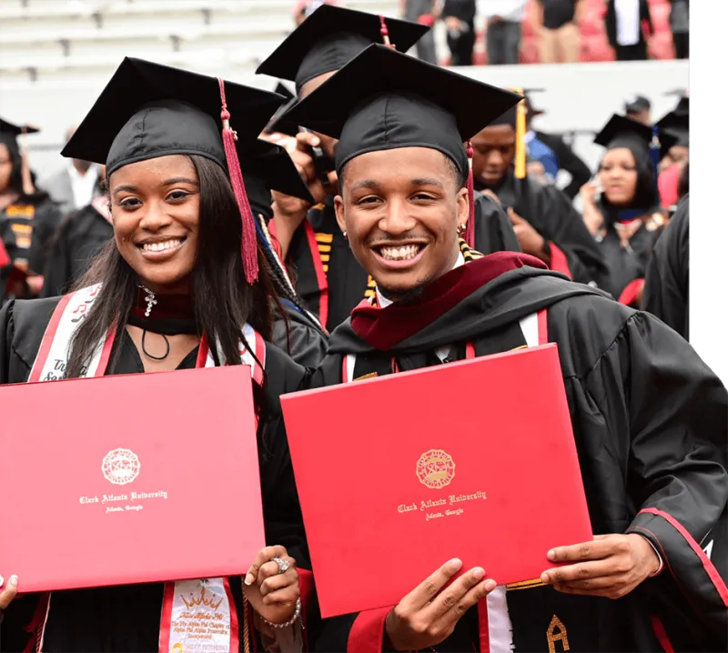 Graduates in caps and gowns smiling, holding diplomas.
