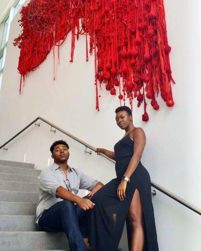 Two people on stairs beneath red abstract wall art.
