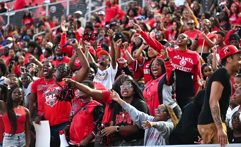 Cheering crowd at a sports event, wearing red and black attire.