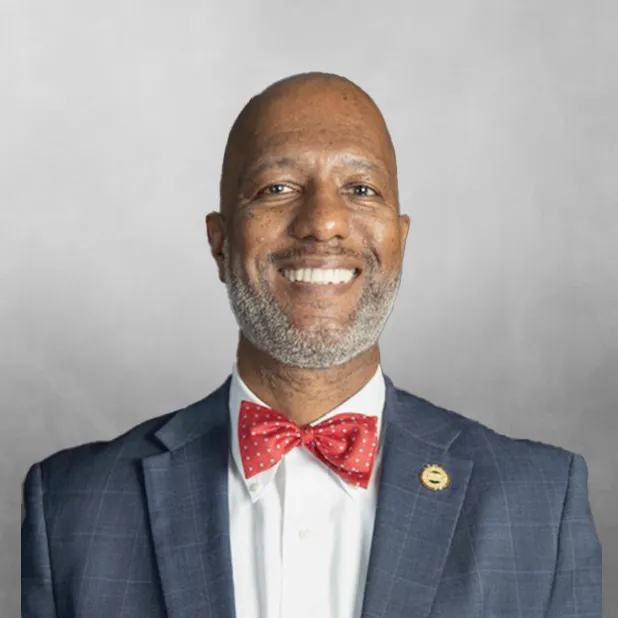 Smiling man in a suit with a red bow tie.
