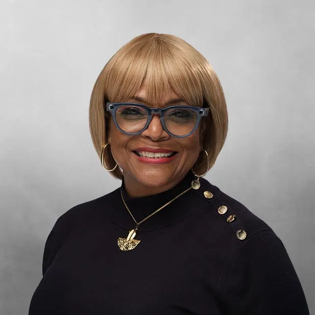 Smiling woman with short blonde hair and glasses, wearing a black top.