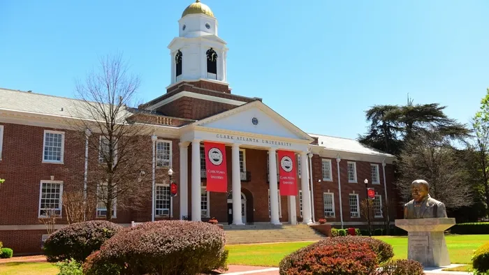 Historic brick building with white columns and banners, sunny day.