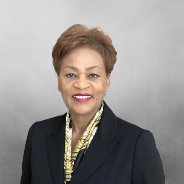 Smiling woman in a suit against a gray background.