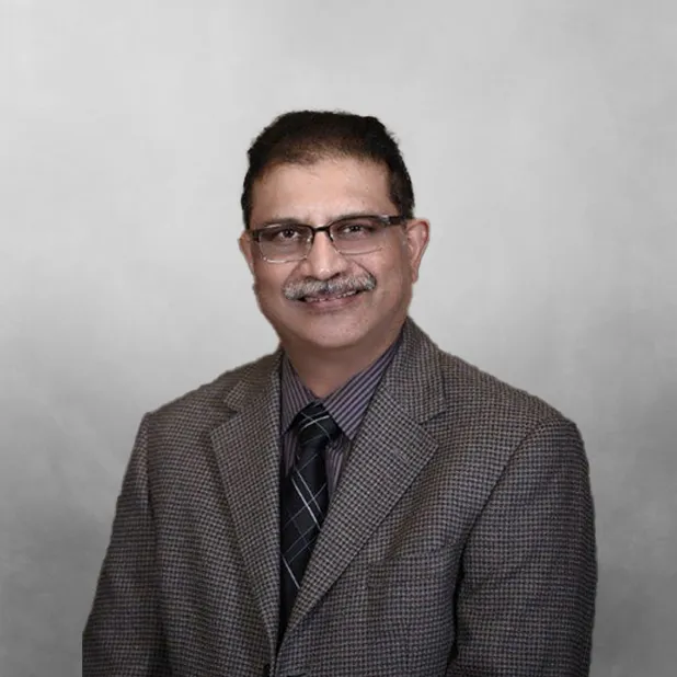 Smiling man in a suit and tie against a gray background.