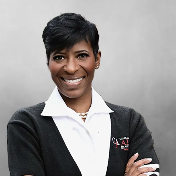 Smiling person with short hair, wearing a collared shirt and sweater.