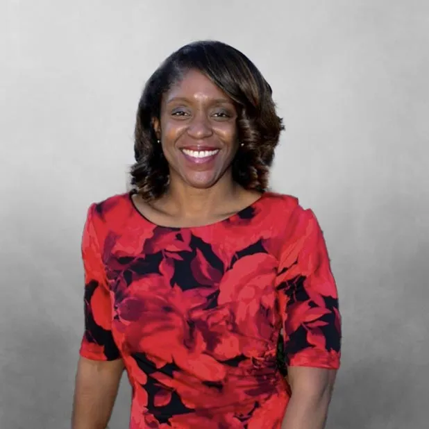 Smiling woman in a red floral dress against a gray background.