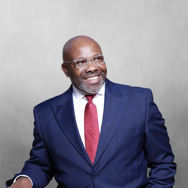 Man in blue suit and red tie smiling against a gray background.