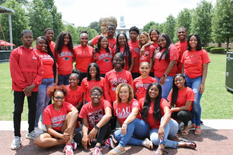Group of people in red shirts smiling outdoors on a sunny day.