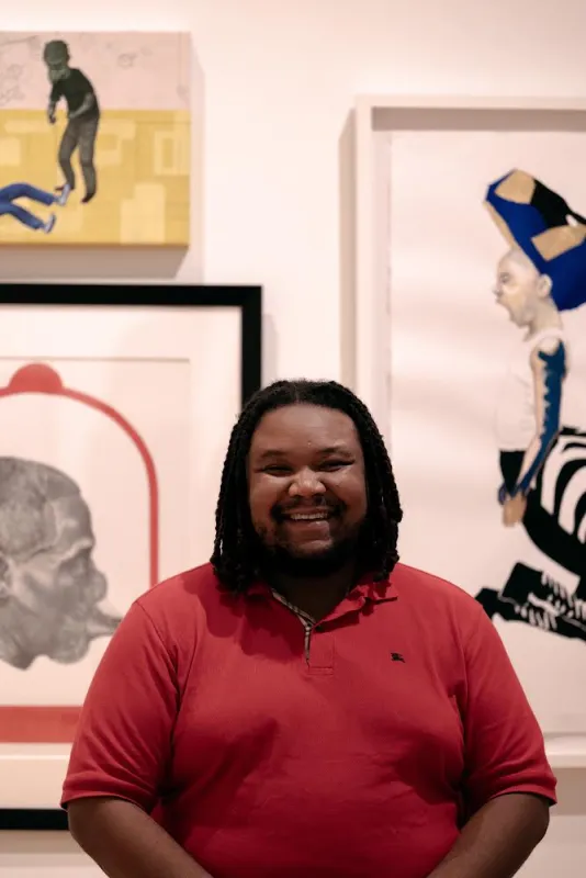Man in red shirt smiling in art gallery.