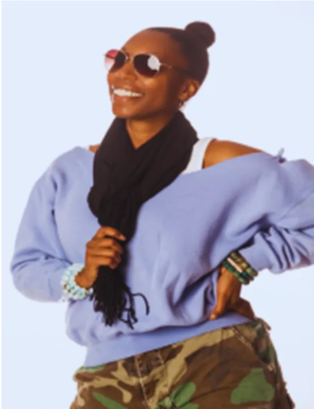 Smiling woman in sunglasses and scarf with casual outfit.