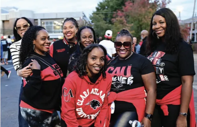 Seven women smiling outdoors, wearing casual outfits in red and black.