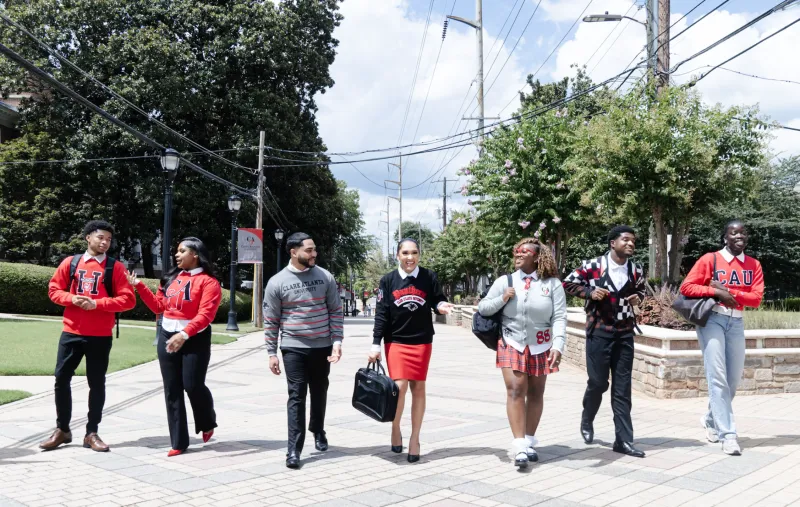 Students walking on a sunny campus path, wearing school attire.