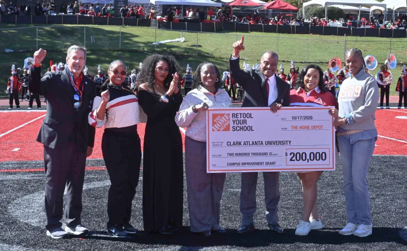 Group holding a large check at a sports event, smiling and celebrating.